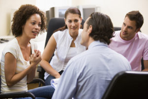 Man giving lecture to three people in computer room